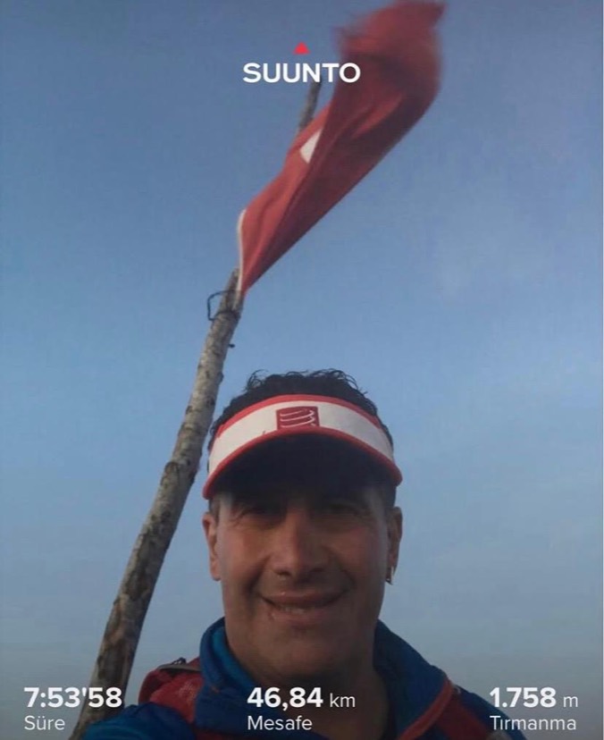 Erden Giritli taking a selfie on a mountain endurance route beside a Turkish flag
