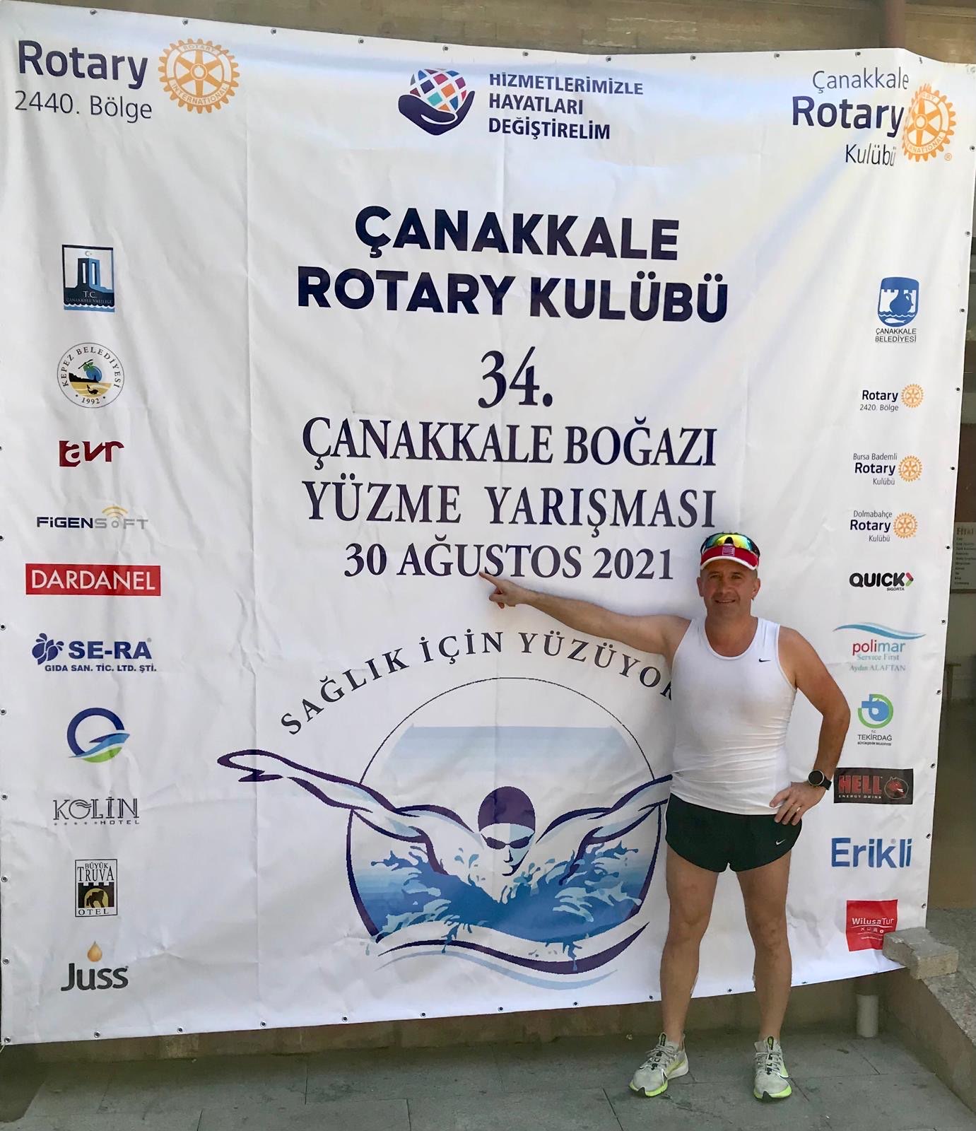 Erden Giritli in front of a Bosphorus swim race banner, reflecting his swimming coach and open water experience