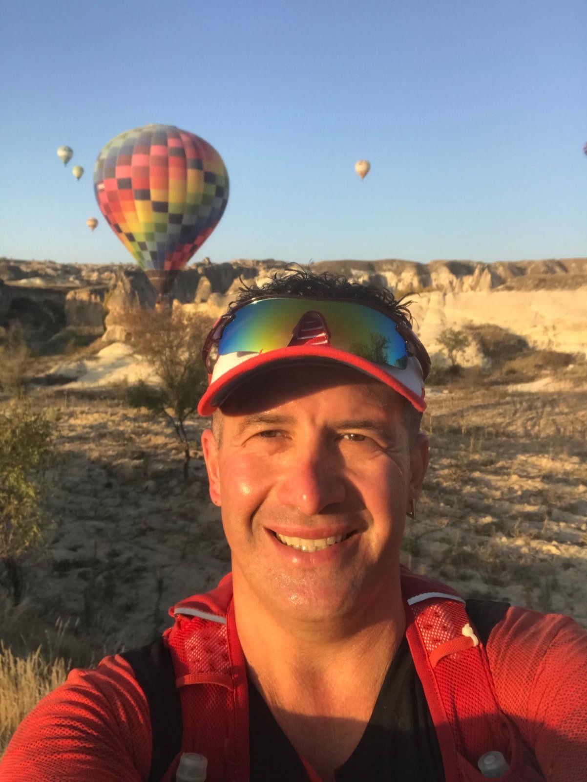 Erden Giritli taking a selfie in front of Cappadocia balloons, reflecting his running coach identity