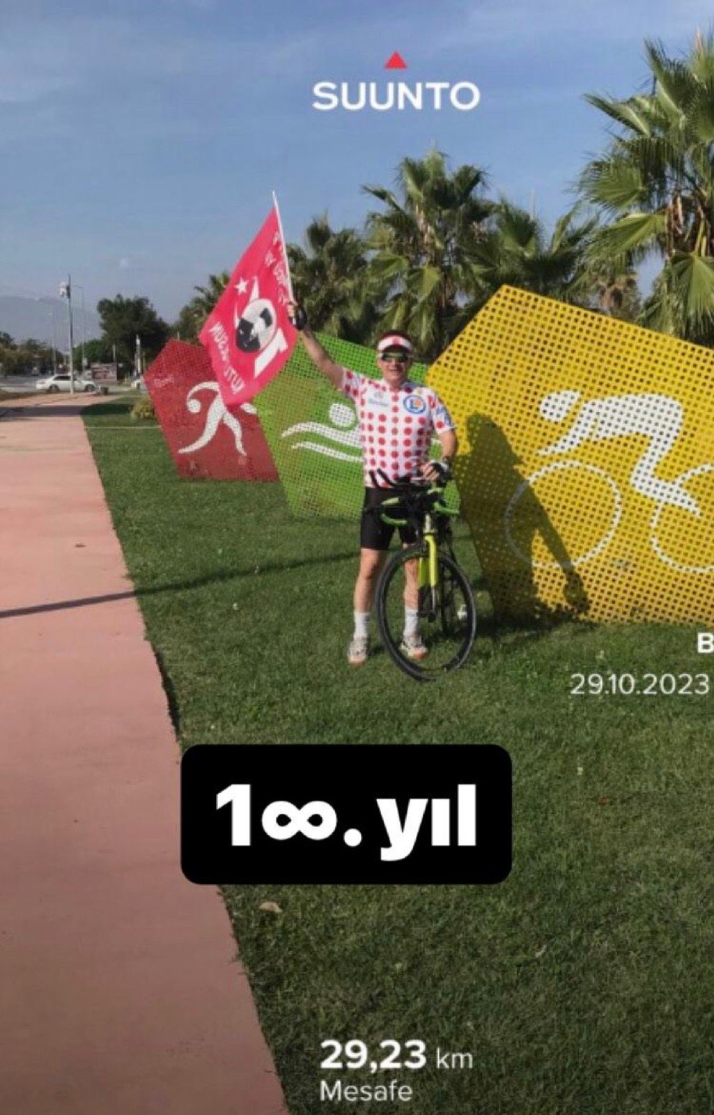 Erden Giritli with his bike at a centennial event, reflecting his triathlon coach and endurance sport identity