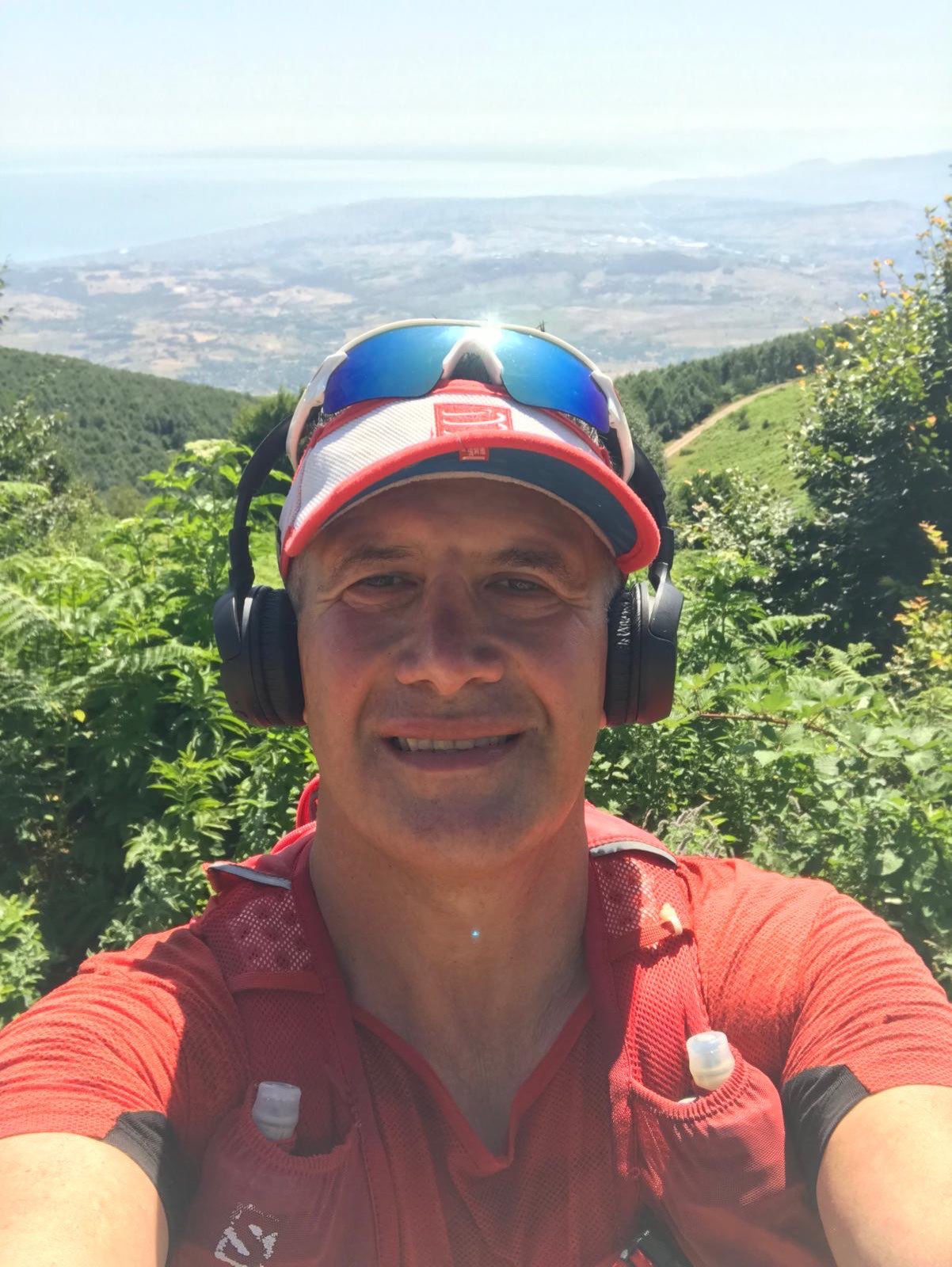 Erden Giritli in front of a mountain view, reflecting his running coach and endurance sport coaching experience