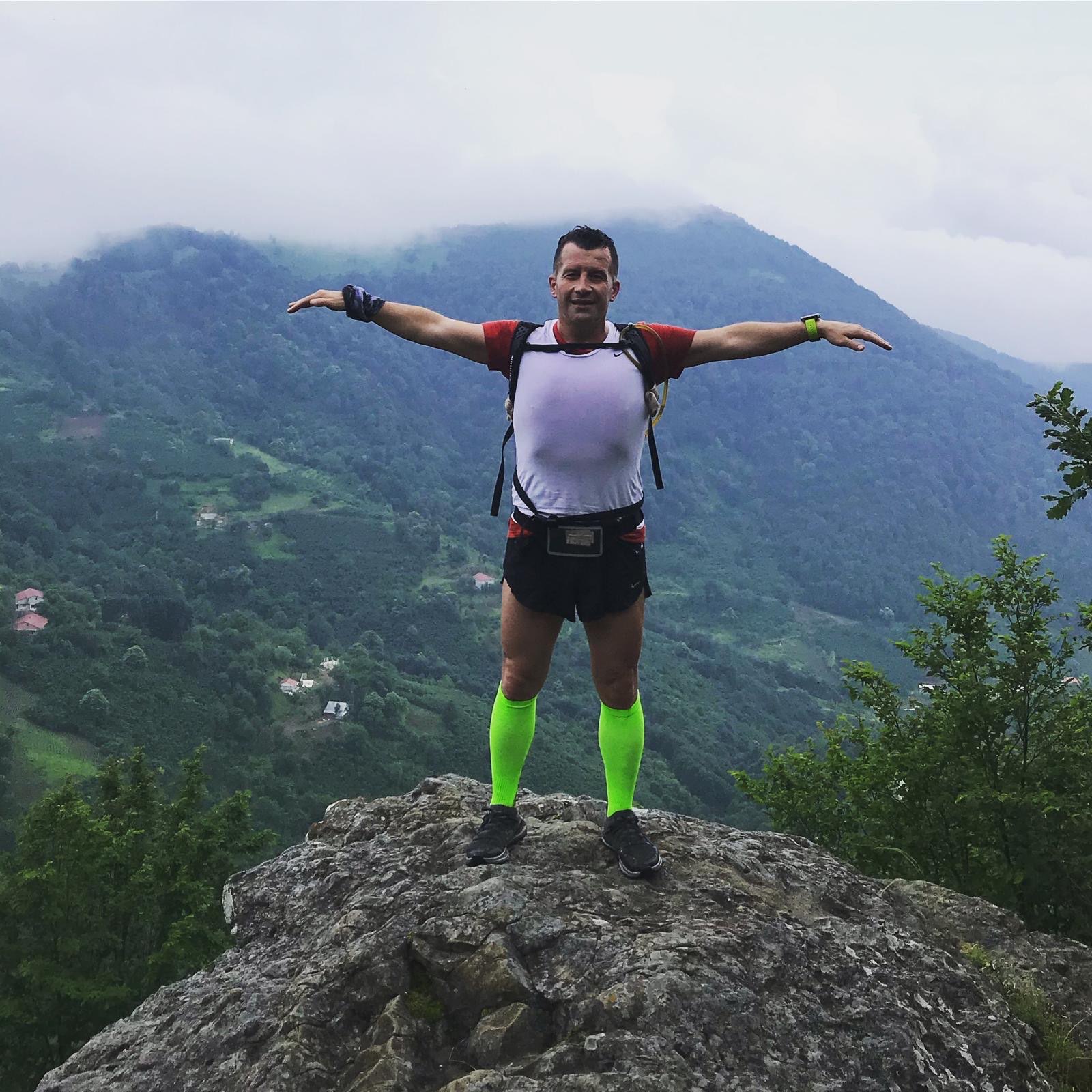 Erden Giritli on a mountain rock viewpoint, reflecting trail running and endurance coaching experience
