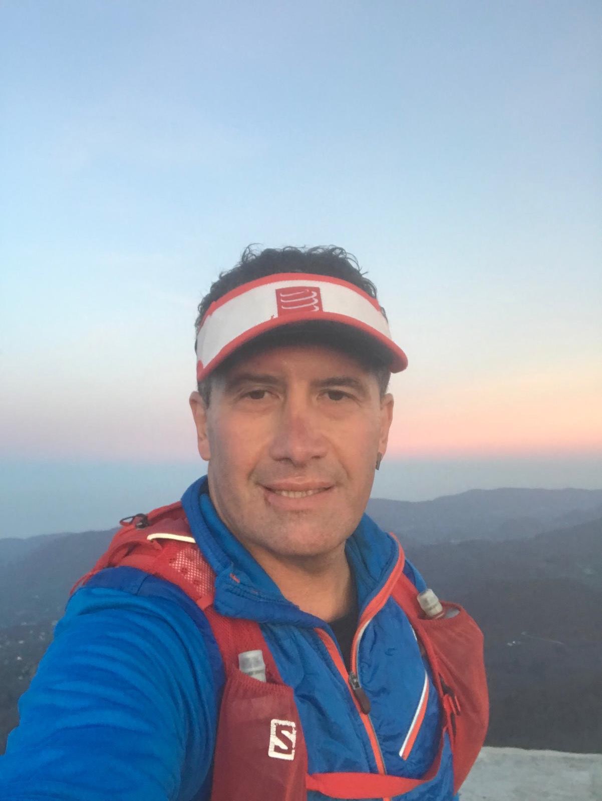 Erden Giritli taking a selfie at a mountain summit, reflecting his endurance coach and trail running experience