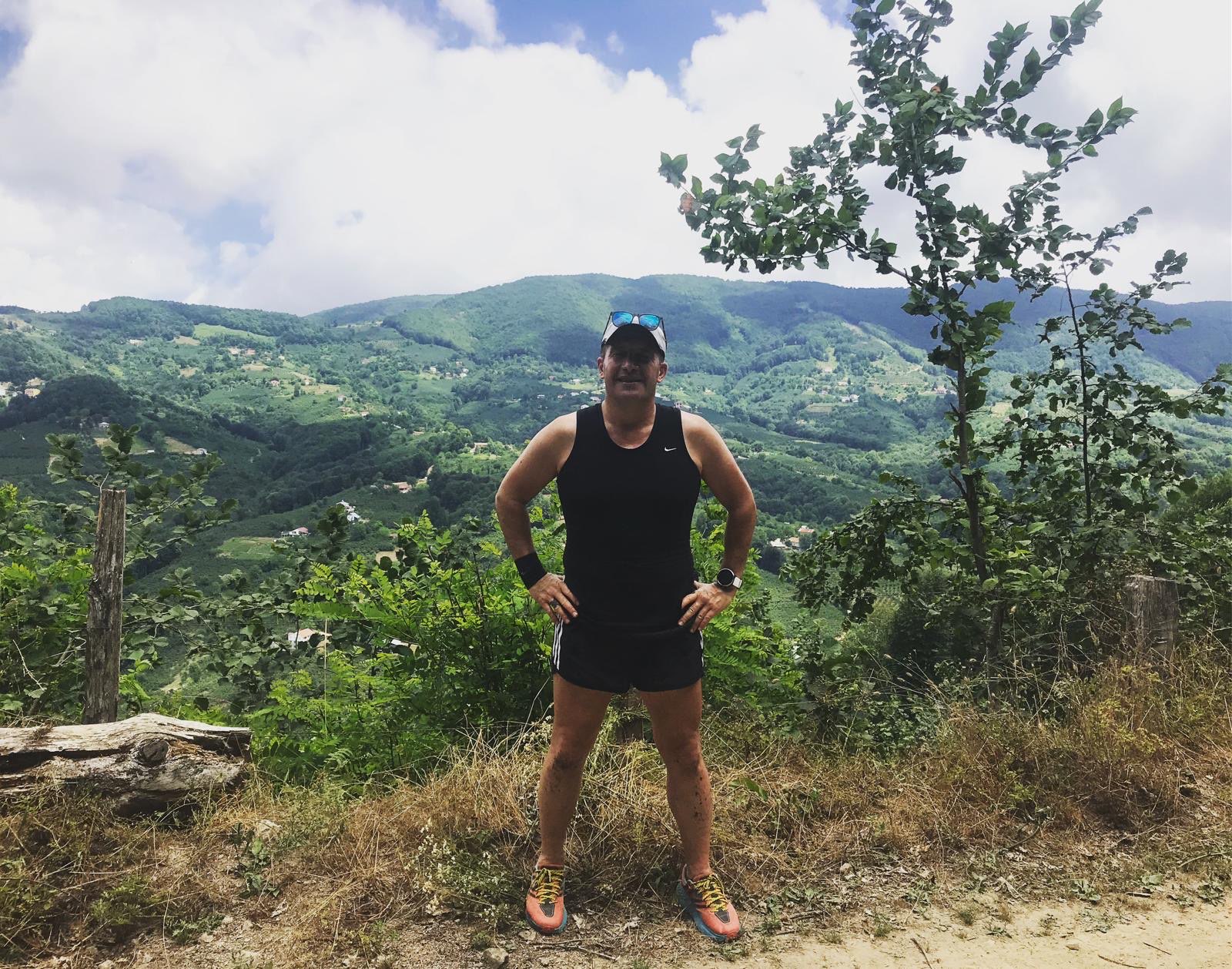 Erden Giritli on a mountain trail with a valley view, reflecting his endurance coach and trail running experience