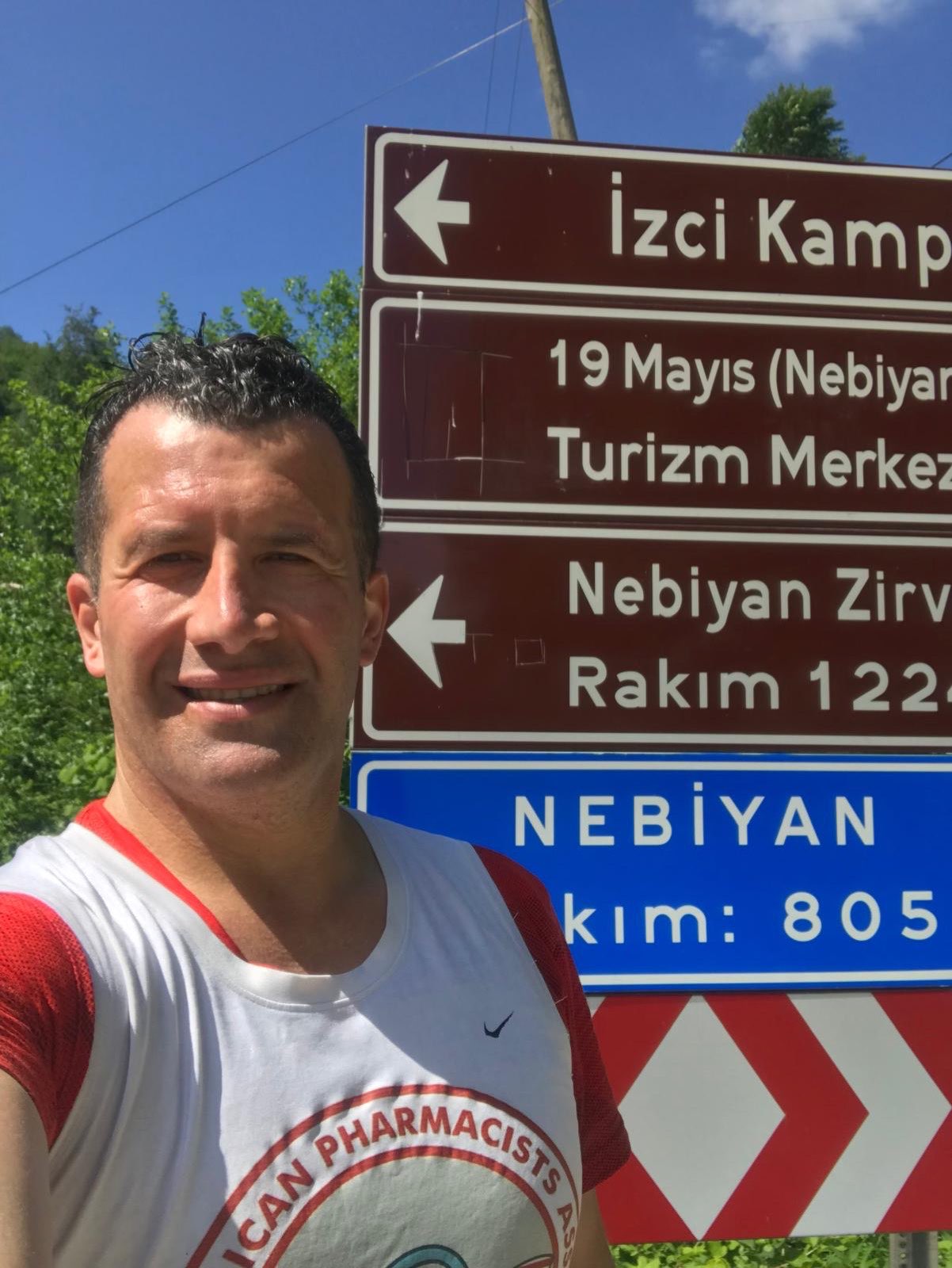 Erden Giritli taking a selfie beside the Nebiyan summit sign, reflecting his trail running coach experience
