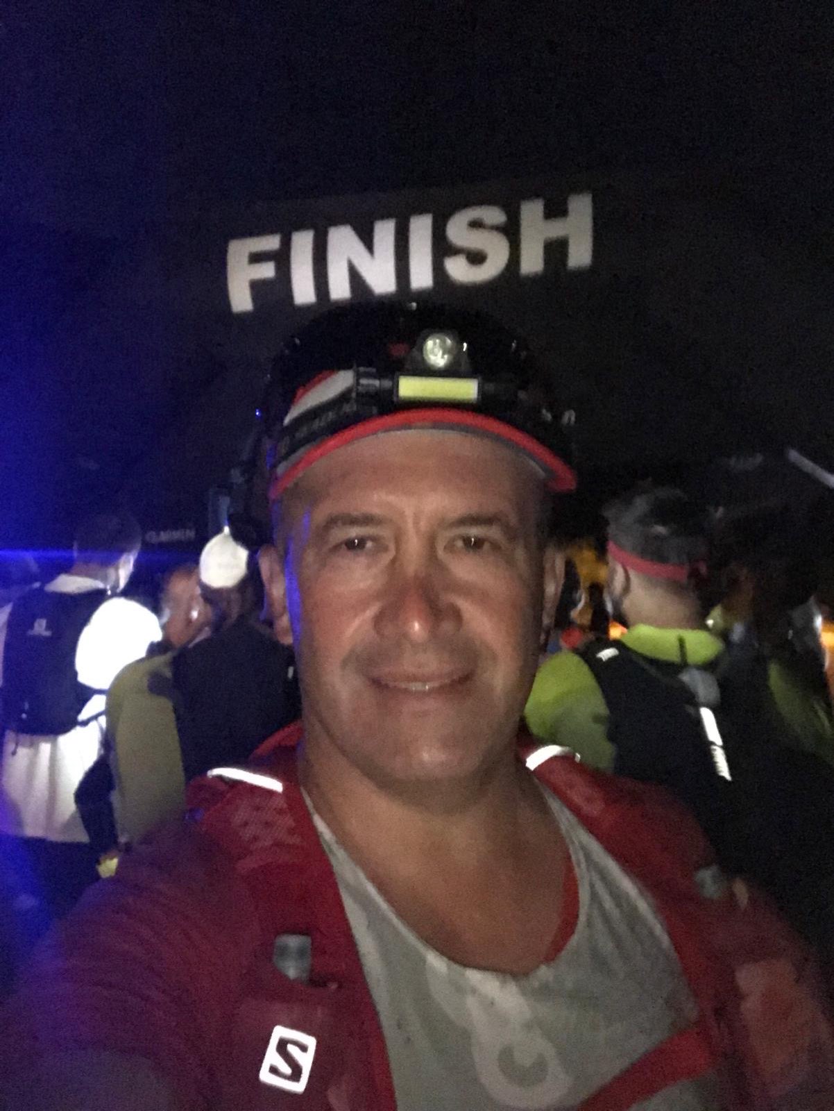Erden Giritli taking a selfie at a night race finish area, reflecting his running coach experience