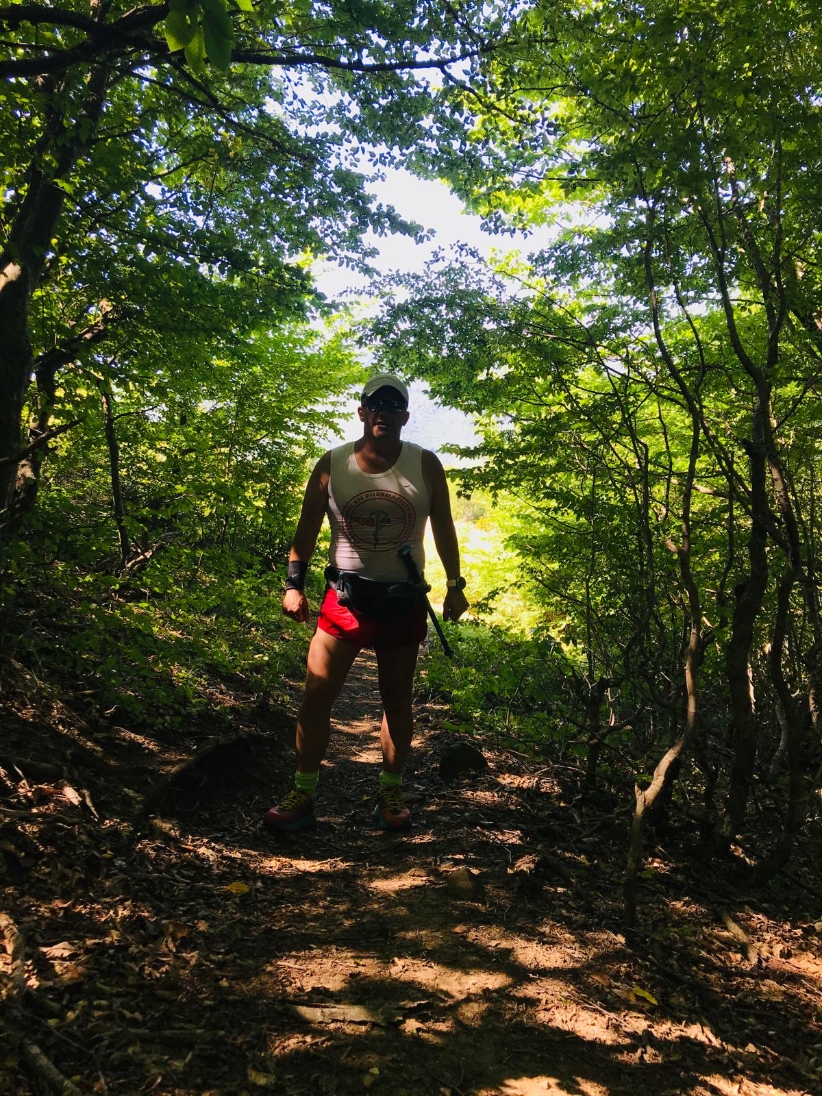 Erden Giritli on a shaded forest path, reflecting his running coach and trail running experience